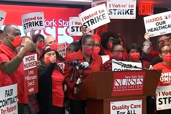 a group of nurses in new york city nurses strike on podium holding protest signs