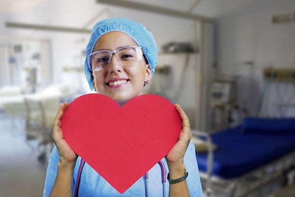 nurse holding red heart shape at a hospital room 