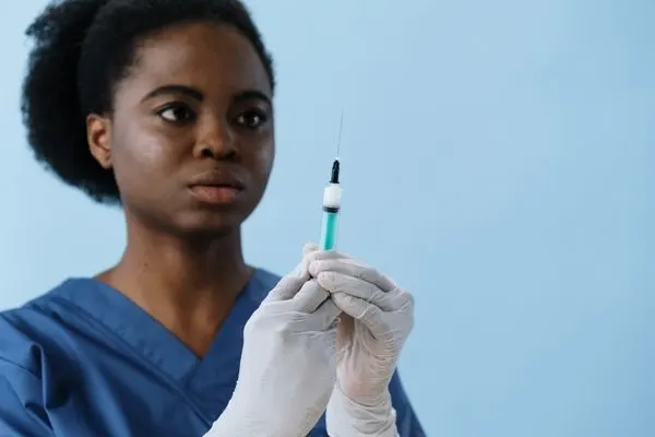 nurse holding up a needle with blue background