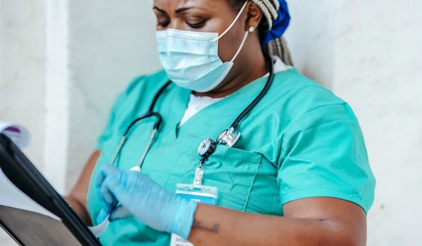 nurse wearing stethoscope and mask checking chart