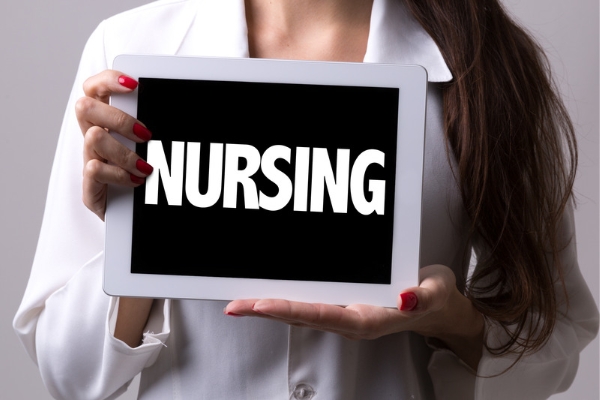 A nurse holding a sign with nursing written on it