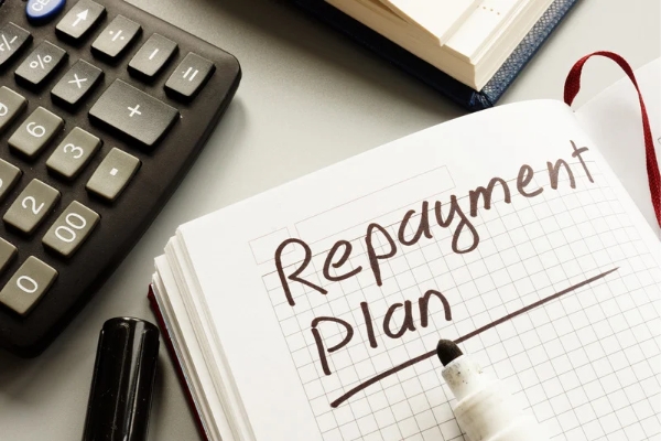 A repayment plan illustration with a notebook, a calculator and marker 