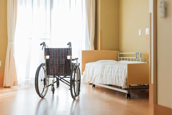 Nursing home with a wheelchair alongside a bed