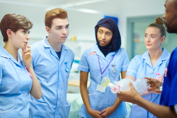 A group of nursing students being guided by a professional nurse