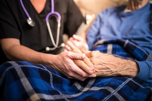A visiting nurse holding hands of a elderly