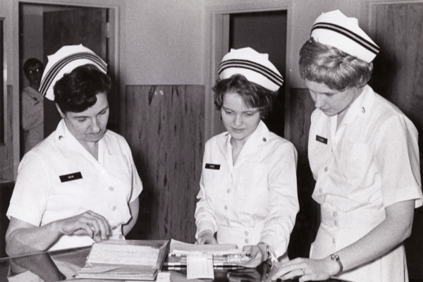 An old image of nurses wearing nurse hats at work