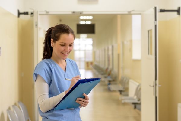 nurse completing chart in hospital hallway
